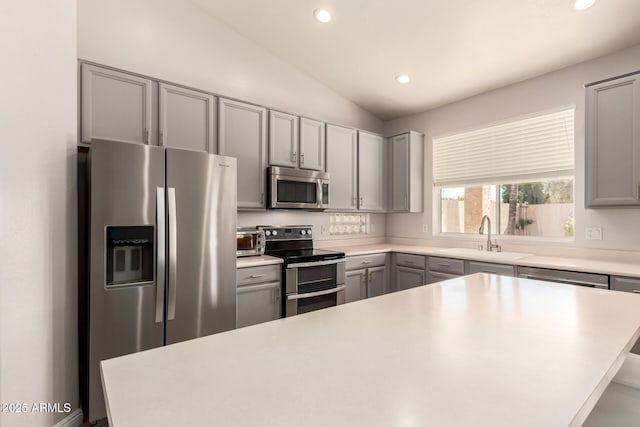 kitchen featuring lofted ceiling, sink, stainless steel appliances, and gray cabinetry