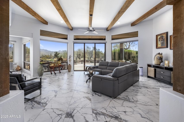 living room featuring marble finish floor, beamed ceiling, a mountain view, and a ceiling fan