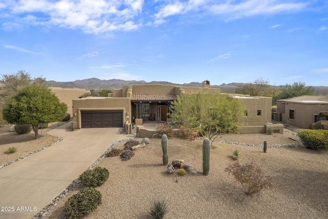 southwest-style home featuring central AC unit, a mountain view, a garage, driveway, and stucco siding