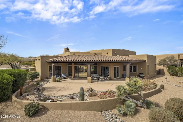 rear view of house with a patio area, a tiled roof, and stucco siding