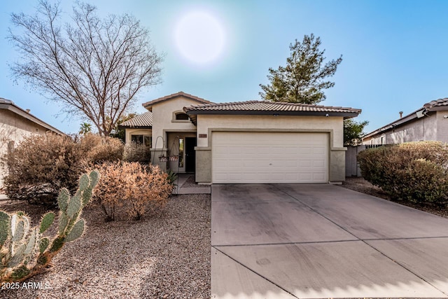 view of front of house featuring a garage, concrete driveway, a tile roof, and stucco siding