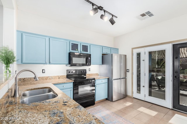 kitchen featuring a sink, visible vents, blue cabinetry, black appliances, and glass insert cabinets