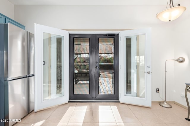 doorway to outside featuring baseboards, light tile patterned flooring, and french doors