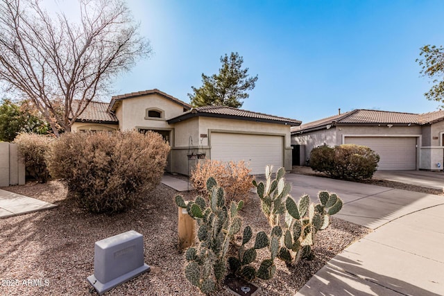 view of front of home featuring driveway, an attached garage, a tiled roof, and stucco siding