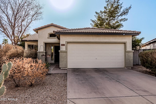 mediterranean / spanish home featuring a garage, concrete driveway, a tiled roof, and stucco siding