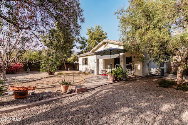 rear view of property with central air condition unit, stucco siding, a patio, and fence