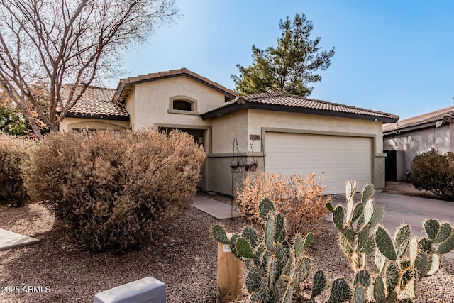 mediterranean / spanish house featuring an attached garage, driveway, a tile roof, and stucco siding