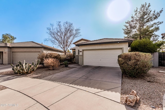 view of front facade featuring an attached garage, a tile roof, concrete driveway, and stucco siding