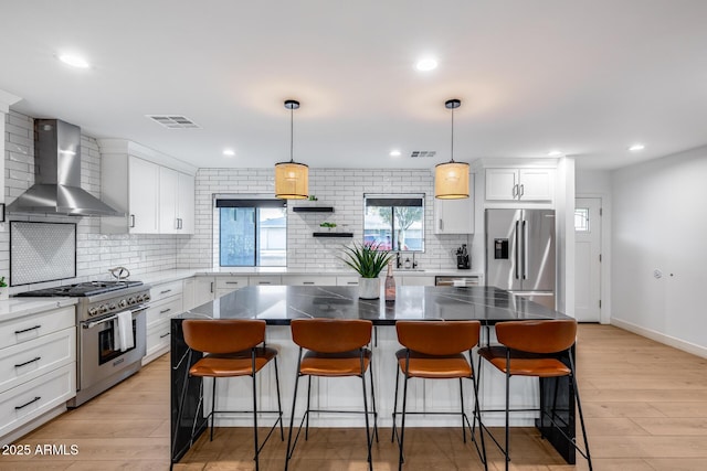 kitchen with decorative backsplash, visible vents, white cabinets, stainless steel appliances, and wall chimney exhaust hood