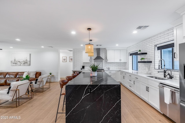 kitchen featuring a sink, a kitchen breakfast bar, open floor plan, stainless steel dishwasher, and visible vents