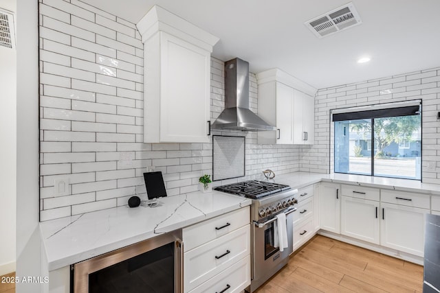 kitchen featuring decorative backsplash, visible vents, high end stainless steel range, beverage cooler, and wall chimney exhaust hood