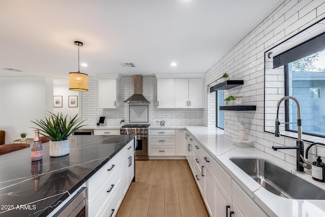 kitchen featuring a sink, wall chimney range hood, backsplash, and stainless steel appliances