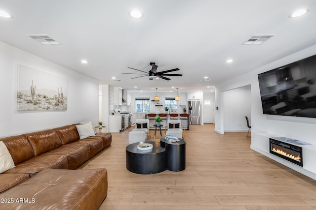 living area featuring light wood finished floors, a ceiling fan, recessed lighting, and visible vents