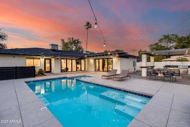 exterior space with a patio, an in ground hot tub, stucco siding, and a fenced in pool