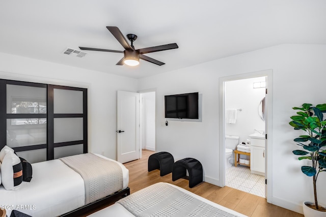 bedroom featuring ceiling fan, ensuite bath, light wood-style floors, baseboards, and visible vents