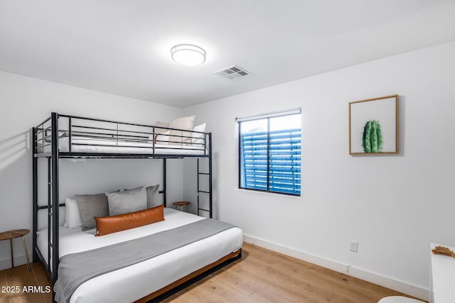 bedroom with baseboards, wood finished floors, and visible vents