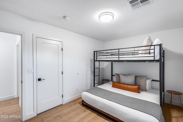 bedroom with baseboards, visible vents, and light wood-type flooring