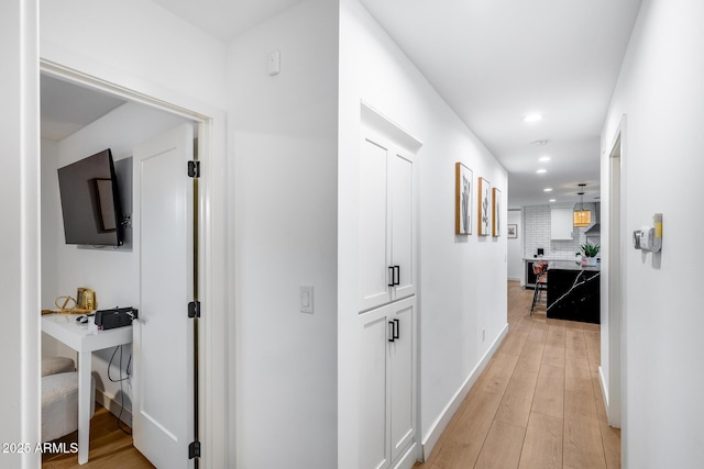 hallway with baseboards, recessed lighting, and light wood-style flooring