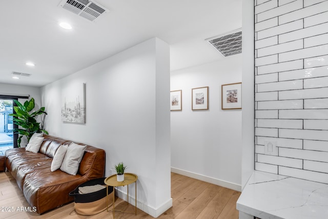 living area with baseboards, light wood-style flooring, and visible vents