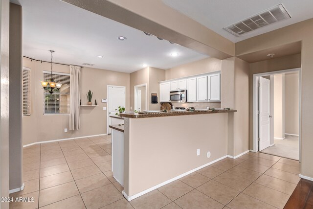 kitchen featuring an inviting chandelier, white cabinetry, kitchen peninsula, and pendant lighting