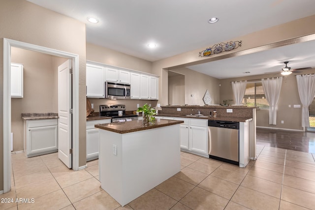 kitchen with appliances with stainless steel finishes, a center island, ceiling fan, and white cabinets