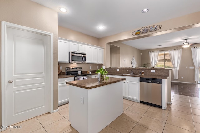 kitchen featuring white cabinets, stainless steel appliances, a center island, ceiling fan, and sink