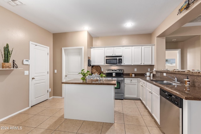 kitchen with light tile patterned flooring, sink, kitchen peninsula, white cabinetry, and appliances with stainless steel finishes