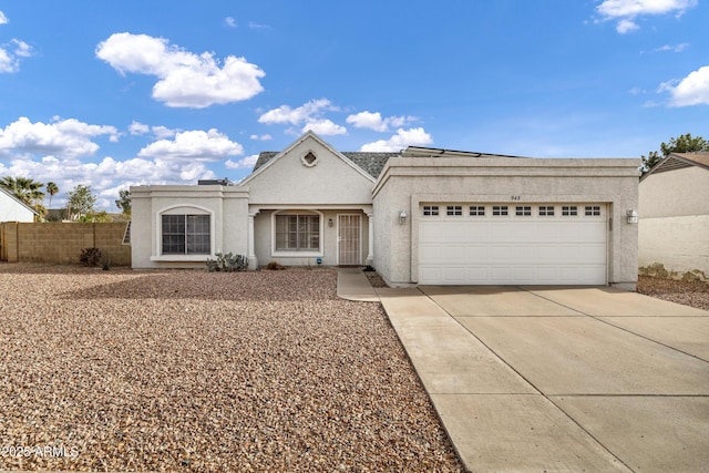 view of front facade with a garage, concrete driveway, fence, and stucco siding