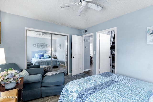 bedroom with a textured ceiling, wood finished floors, visible vents, and a ceiling fan