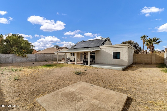 back of property featuring a patio area, a fenced backyard, solar panels, and stucco siding