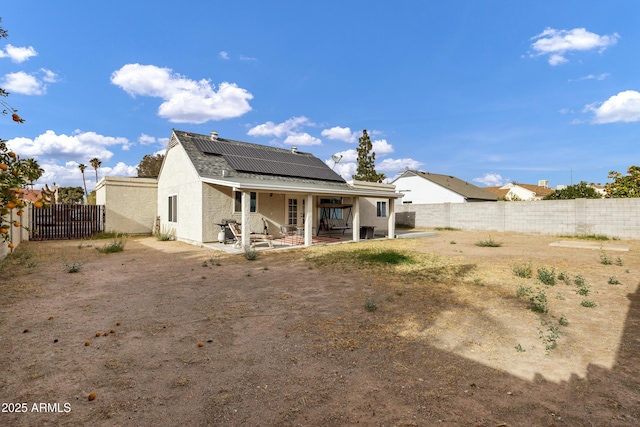 back of house featuring a patio, solar panels, a fenced backyard, and stucco siding