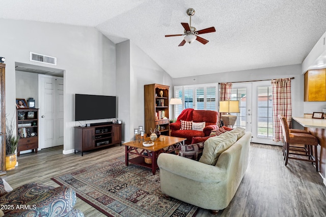 living room featuring french doors, plenty of natural light, wood finished floors, and visible vents