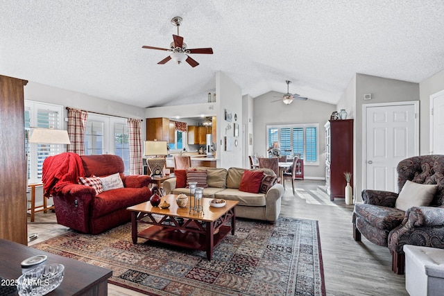 living room with a textured ceiling, vaulted ceiling, wood finished floors, and french doors