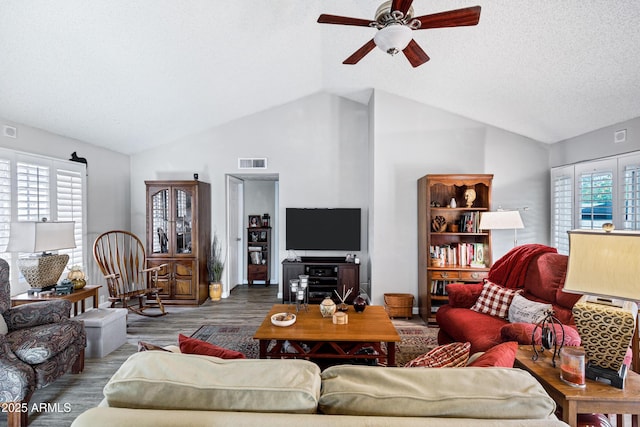 living room featuring lofted ceiling, a healthy amount of sunlight, visible vents, and wood finished floors