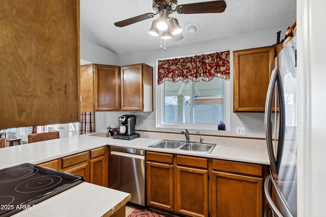 kitchen featuring light countertops, stainless steel dishwasher, freestanding refrigerator, a sink, and a textured ceiling