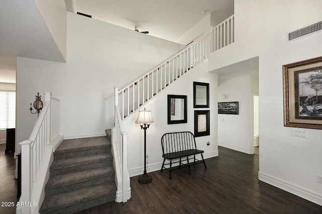 staircase featuring a towering ceiling and wood-type flooring