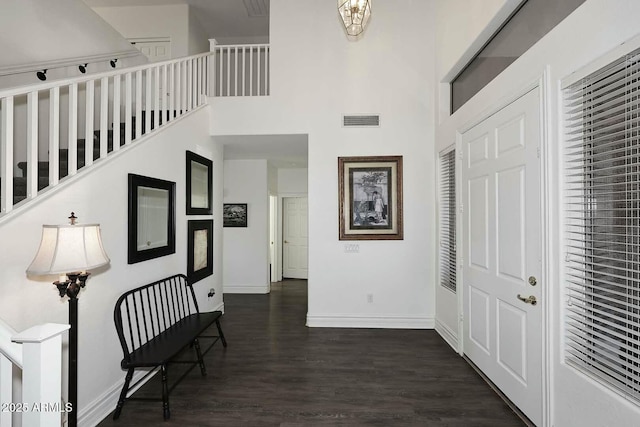 corridor with dark hardwood / wood-style floors and a towering ceiling