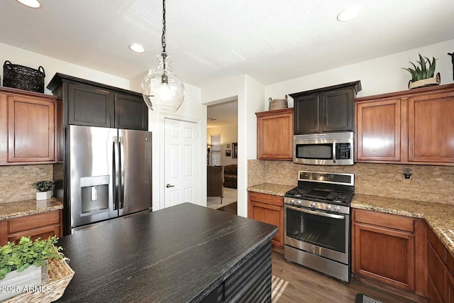 kitchen with tasteful backsplash, hanging light fixtures, light stone counters, stainless steel appliances, and dark wood-type flooring