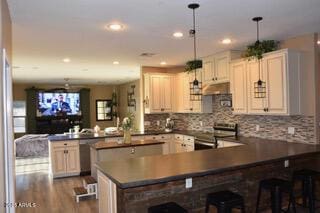 kitchen featuring hanging light fixtures, kitchen peninsula, wood-type flooring, a breakfast bar area, and appliances with stainless steel finishes