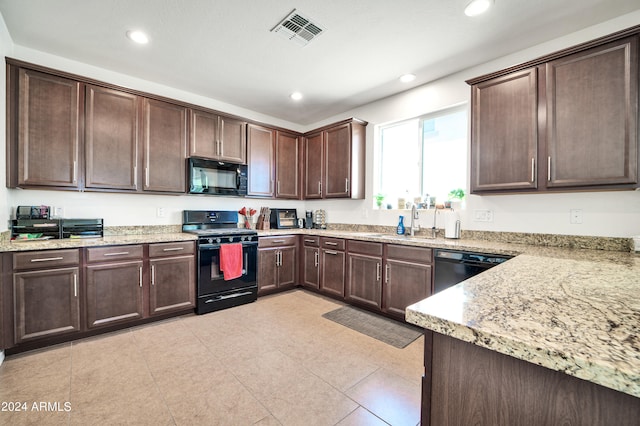 kitchen featuring black appliances, light stone counters, sink, and dark brown cabinets