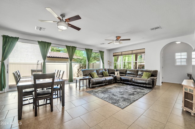 tiled living room with a textured ceiling, a healthy amount of sunlight, and ceiling fan