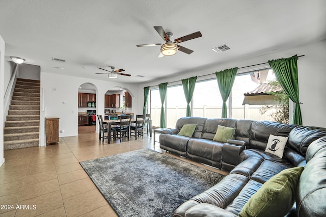 living room with tile patterned flooring, ceiling fan, and a textured ceiling