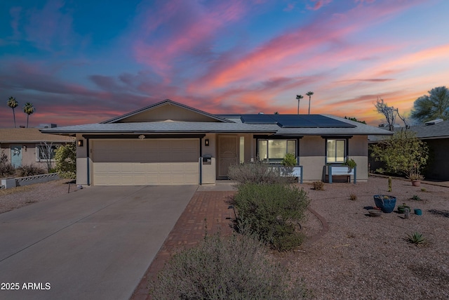 ranch-style home with roof mounted solar panels, stucco siding, driveway, and an attached garage