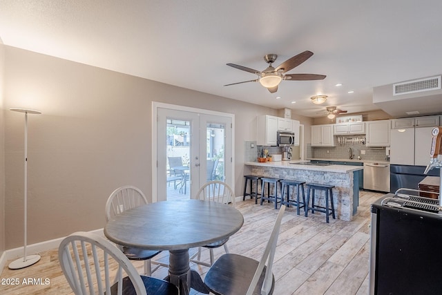 dining room featuring baseboards, visible vents, ceiling fan, french doors, and light wood-type flooring