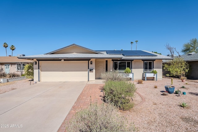 single story home with solar panels, concrete driveway, an attached garage, and stucco siding