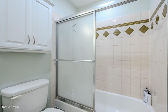 bathroom with bath / shower combo with glass door and toilet