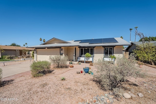 ranch-style home with solar panels, an attached garage, driveway, and stucco siding