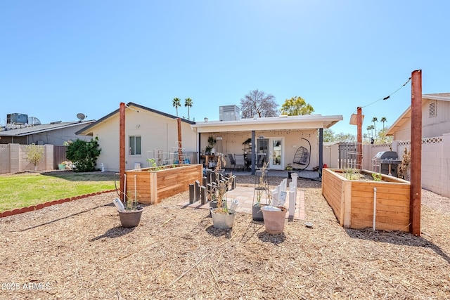 back of house with a garden, a fenced backyard, and a patio area