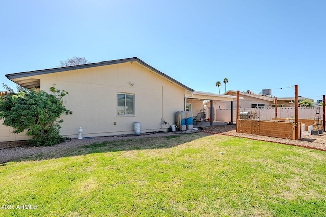 back of property featuring a vegetable garden, a yard, and fence