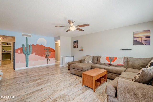 living room with visible vents, baseboards, light wood-style floors, and ceiling fan